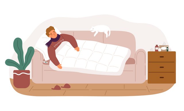 Ein Mann liegt zugedeckt auf einer Couch. Er trägt einen Schal um den Hals und einen dicken Pullover. Neben ihm liegt ein Thermometer. Auf der Couch schläft eine Katze.