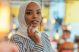 Eine junge Frau mit Hidschab blickt in die Kamera.