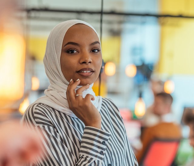 Eine junge Frau mit Hidschab blickt in die Kamera.